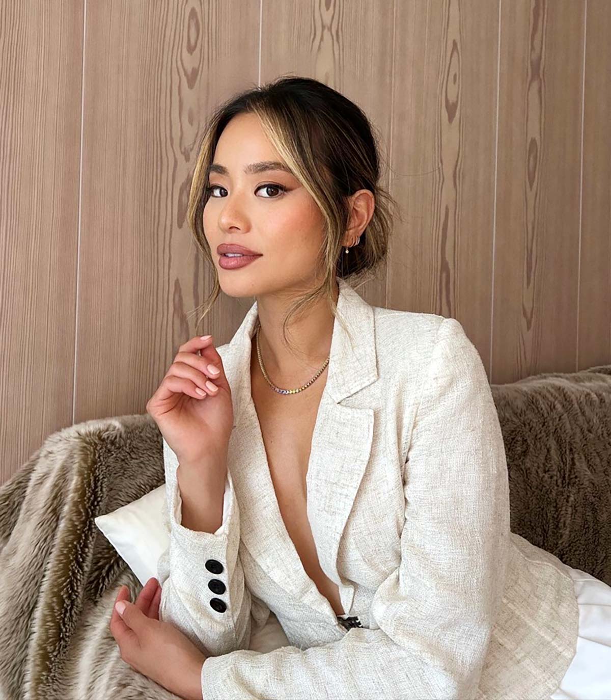 Jamie Chung poses in front of a wood paneled wall.