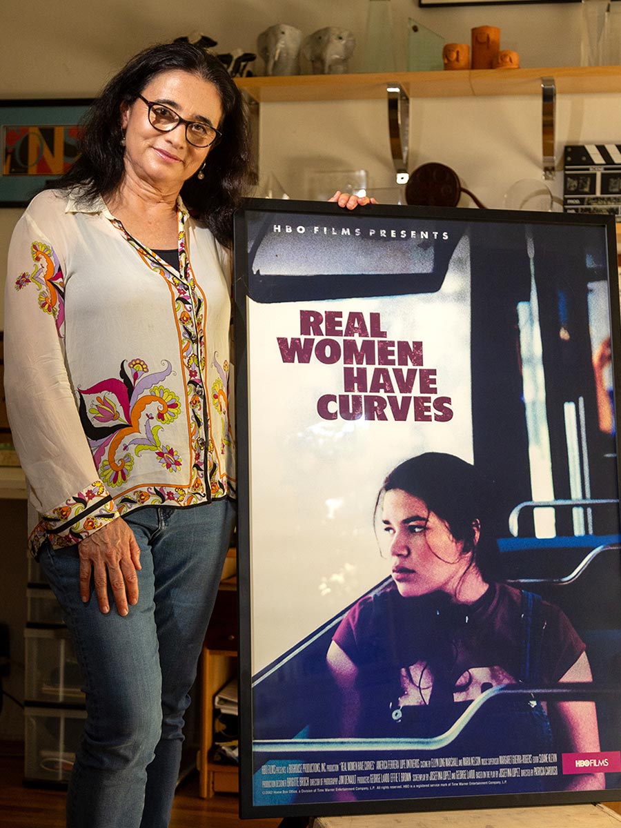 Patricia Cardoso stands next to a poster for the movie 'Real Women Have Curves'.