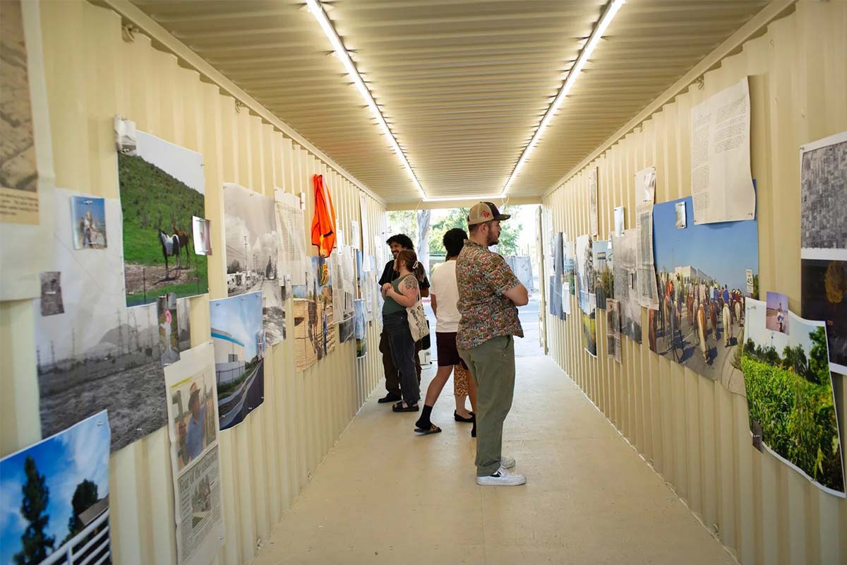 Visitors look at the images and text displayed inside of a shipping container as part of the “Bloomington Speaks” art installation.
