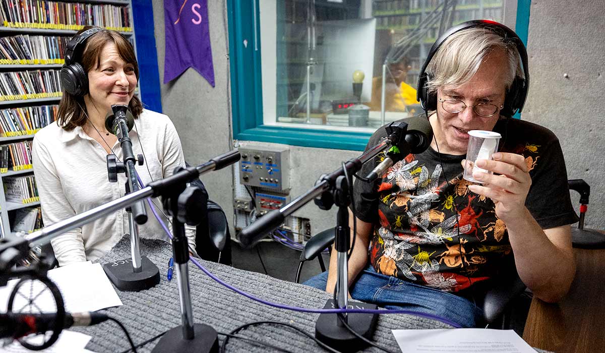 UC Riverside’s entomologist Doug Yanega, right, looks at a spider in a container with cohost Jules Bernstein, Senior Research Communications Manager, during a taping of their podcast, Can I Bug You.